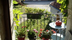 A view through an archway to a courtyard with potted plants and a table.