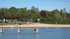 A riverside park with a sandy beach, trees, and a bridge over the water.