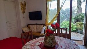 A dining area with a table set for two, a sofa, and a window with curtains. - Sea views, 2 beautiful terraces, charming duplex in villa, landscaped garden   (Brando)