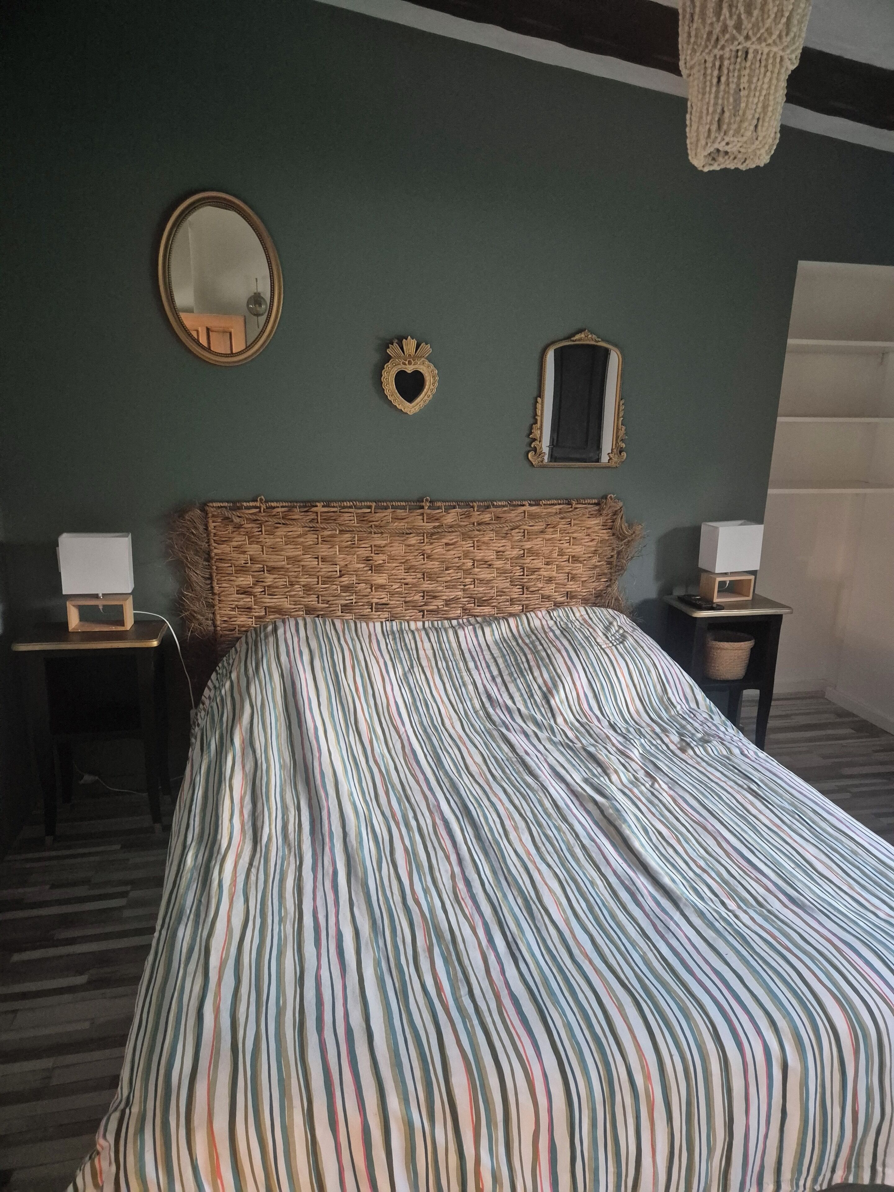 A bed with a striped bedspread, a mirror, and two bedside tables with lamps.