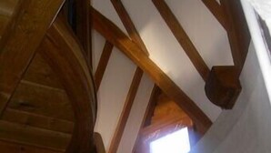 Una escalera de madera con techo inclinado y un pequeño ventanal en la parte superior.