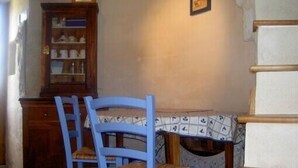 Una habitación con un armario de madera, una silla azul y un mantel estampado.