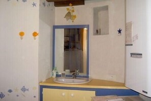 Une salle de bain avec un lavabo, un miroir et une petite fenêtre.