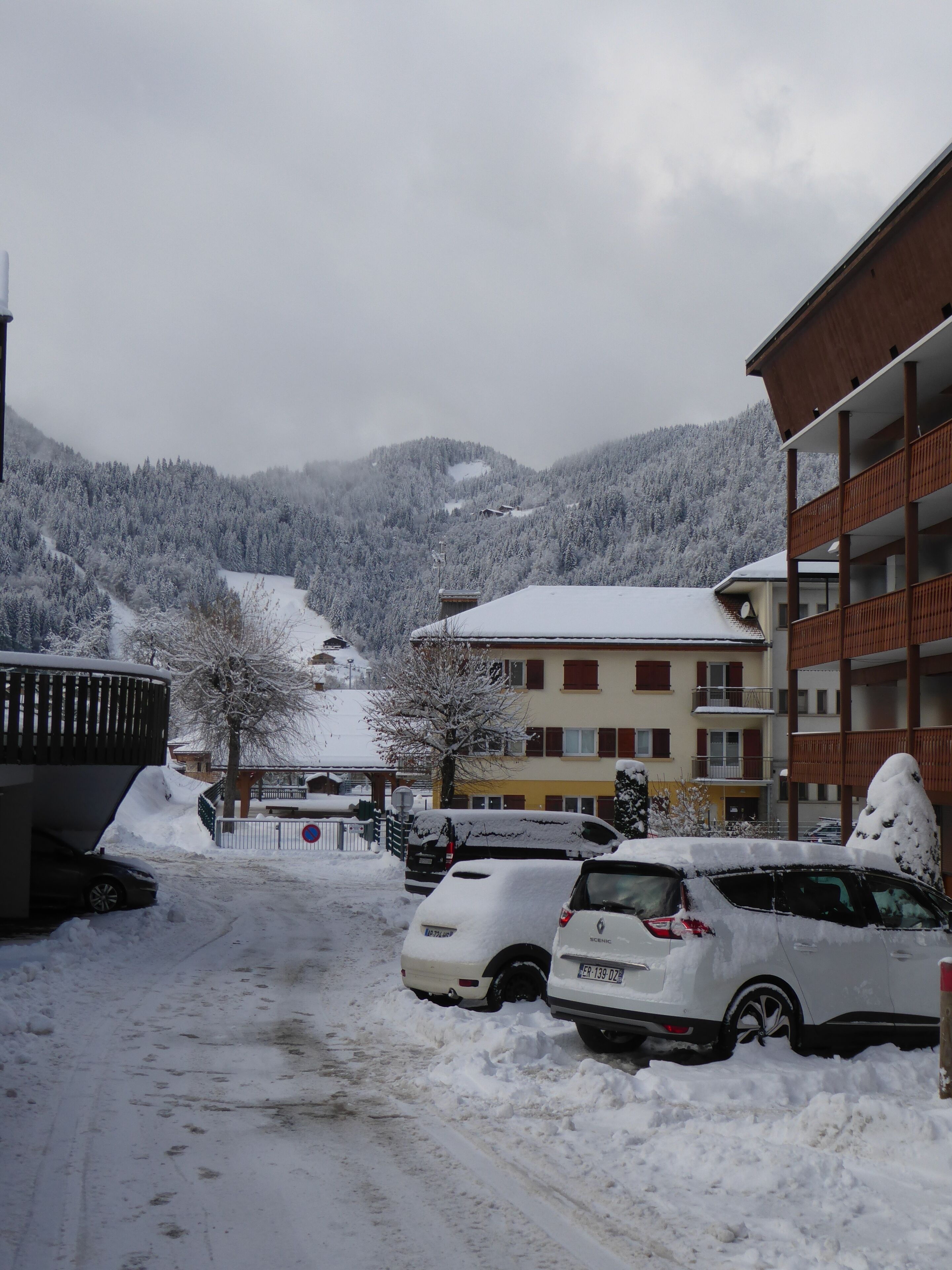 A snowy parking area with a building in the background.