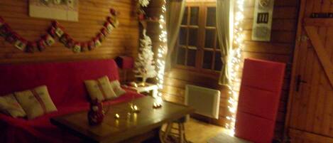 Un'accogliente stanza con arredamento in legno, un divano rosso, un tavolino e un albero di Natale.