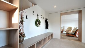 Ein modernes Interieur mit eingebauter Bank, Wandhaken, einem dekorativen Kranz und einer Sitzecke mit Korbstühlen.