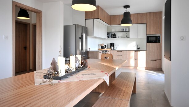 Eine moderne Küche mit einer langen Holzausziehtheke, integrierten Geräten und Pendelleuchten.