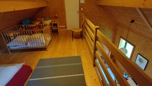 A cozy attic bedroom with a wooden crib, a small desk, and a chair. - Burgundy, cottage, cottage, calm, tranquility, rest, southern Morvan (Corancy)