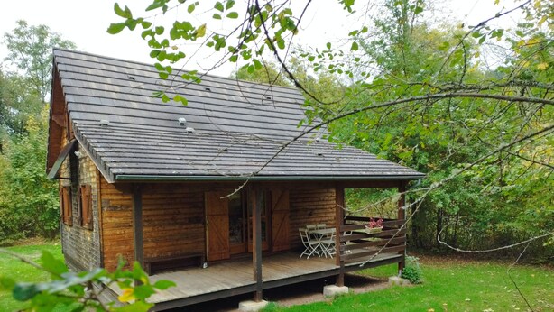 A wooden cabin with a porch and a covered deck, surrounded by greenery. - Burgundy, cottage, cottage, calm, tranquility, rest, southern Morvan (Corancy)