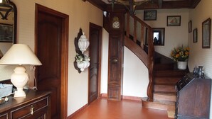 Un escalier en bois, avec une horloge et un vase de fleurs accrochés au mur.