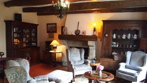 Un salon traditionnel, avec des meubles anciens, une cheminée et un plafond en bois.