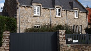 Un bâtiment en pierre doté de nombreuses fenêtres et d’un toit sombre.