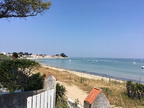 A coastal view with a sandy beach, a clear blue sky, and a row of houses along the shore. - Beautiful farmhouse on large plot of land in Noirmoutier, near town center and sea (Noirmoutier-En-L'île)