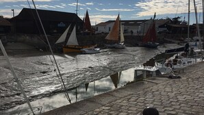 Een waterkant met boten, een brandkraan en gebouwen op de achtergrond.