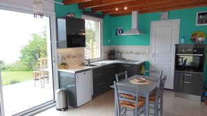 A modern kitchen with a dining area, featuring a large window, wooden ceiling, and a view of the outdoors. - House direct access to the beach from the garden. (Trébeurden)