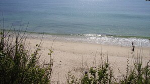 A beach with a person walking along the shore. - House direct access to the beach from the garden. (Trébeurden)