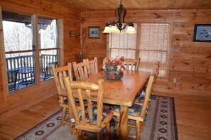A wooden dining room with a table, chairs, and a chandelier.
