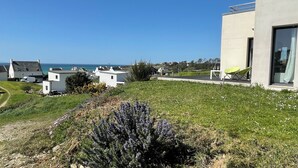 A coastal residential area with white houses, a modern building with large windows, and a clear view of the sea.