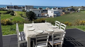 A table set outdoors with a view of houses and the sea.