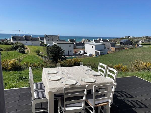Mesa posta ao ar livre com vista para casas e para o mar.
