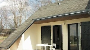 Ein modernes Haus mit Satteldach, einer Terrasse mit Tisch und Stühlen sowie einer Garagentür.