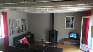 A living room with a sofa, ottoman, and a television. - Renovated house in black Périgord with private pool and wifi for 6/8 people (Montignac)