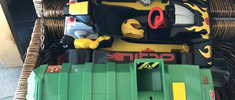 A wicker basket containing various toy vehicles and a green toy car.