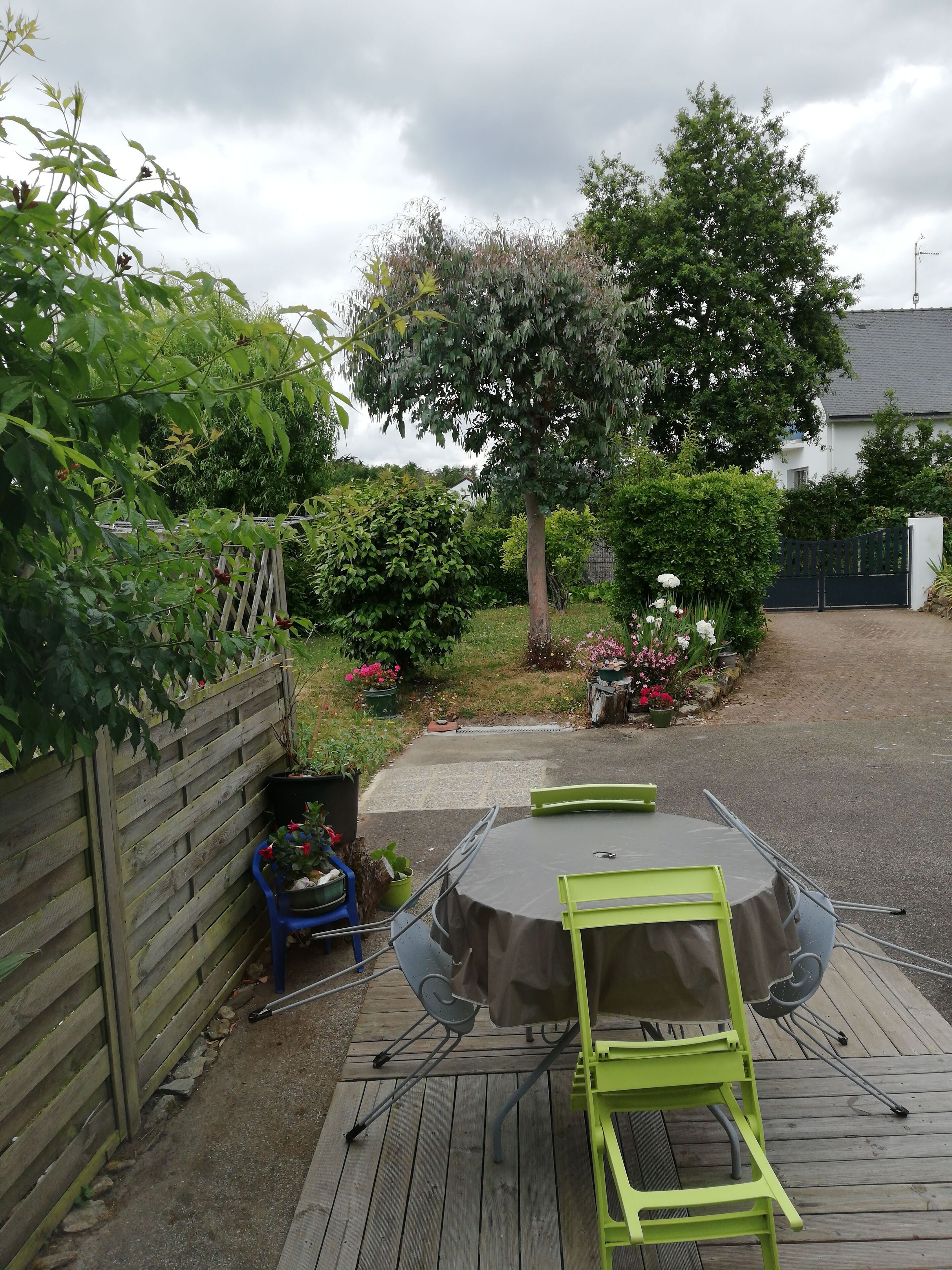 A patio with a round table and chairs, surrounded by a wooden fence and various plants.