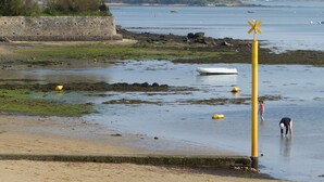 A coastal area with a stone wall, a yellow buoy, and a small boat on the water. - Séné seaside lodging (classified 2 stars) (Séné)