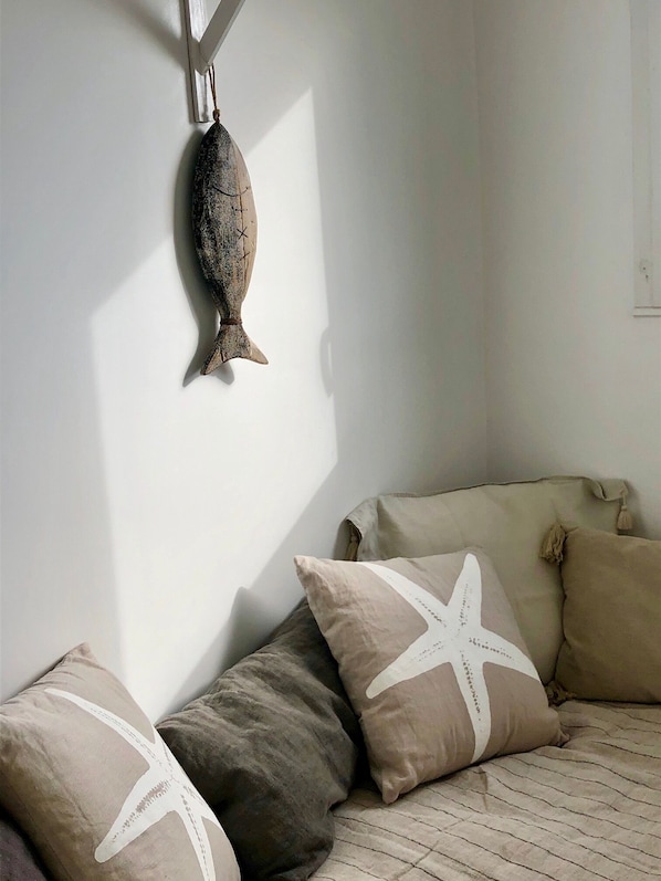 Et værelse med en seng, puder og en fiskedekoration på væggen.
