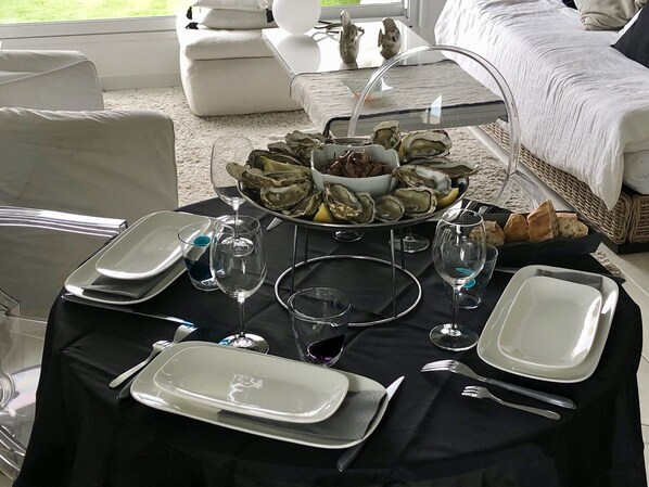 A dining table set with plates, glasses, and a bowl of oysters. - 180° sea view-Terrace-Rooftop-Plage-City center-Fiber-Netflix-Clim-Garage   (Arcachon)
