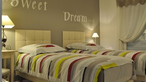 Quarto de hotel com duas camas, uma cabeceira e uma parede com a frase 'Sweet Dream' escrita.