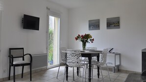 Uma sala de jantar com uma mesa, cadeiras, um vaso com flores e obras de arte na parede.