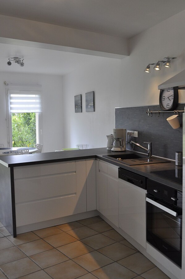 A modern kitchen with a built-in dishwasher, a coffee maker, and a clock on the wall.