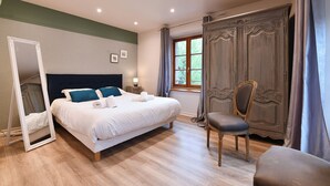A well-lit bedroom with a large bed, a chair, a wardrobe, and a mirror. - Bredala ***, 5-person apartment in the historic center of Colmar - 2 bedrooms (Colmar)