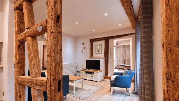A living room with a wooden staircase, a television, a blue sofa, and a dining table. - Bredala ***, 5-person apartment in the historic center of Colmar - 2 bedrooms (Colmar)