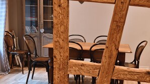 A dining area with a wooden table and chairs, a cabinet with books, and a curtain. - Bredala ***, 5-person apartment in the historic center of Colmar - 2 bedrooms (Colmar)
