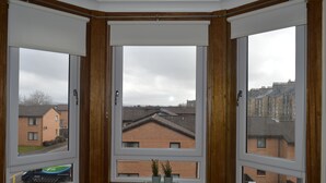 Kolmella lasiruudulla varustettu erkkeri-ikkuna, josta avautuu näkymä asuinalueelle.