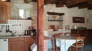 Une cuisine rustique avec des meubles en bois, un pare-feu en carreaux et un coin repas comprenant une table et des chaises.