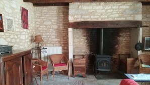 Une pièce rustique avec un mur en pierre, une cheminée, des meubles en osier et un buffet en bois.