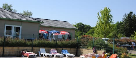 A swimming pool area with lounge chairs and umbrellas.