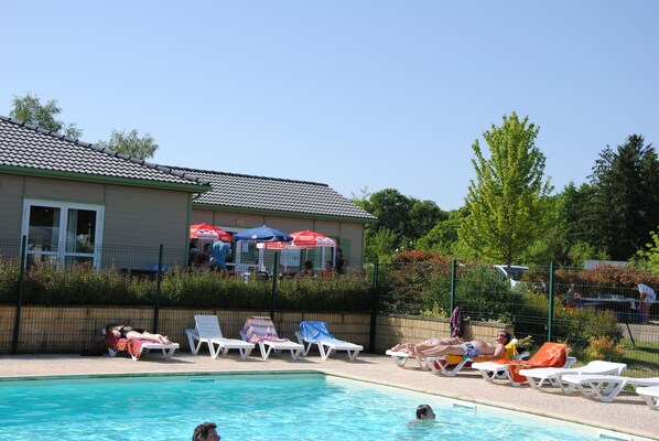 A swimming pool area with lounge chairs and umbrellas.
