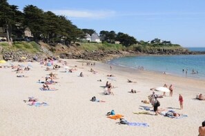 Une plage bondée où les gens se prélassent au soleil et se baignent.