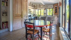 Une cuisine avec une table ronde, des chaises, des meubles de rangement en bois et une fenêtre.