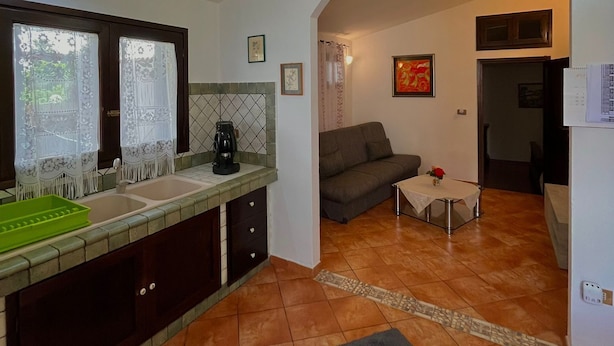 Uma cozinha com pia, cafeteira e área de jantar com mesa e sofá.