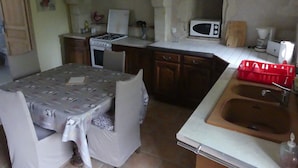 Une cuisine compacte comprenant une table à manger, un évier, un four à micro-ondes et une cuisinière.