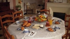 A dining table set with breakfast items including croissants, cheese, fruit, and juice.