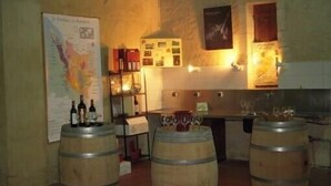 A bar area with wooden barrels, a menu board, and wine glasses.
