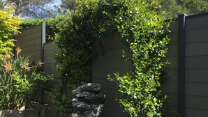 A garden with a rock feature, a wooden bench, and a wall with climbing plants. - House for rent gulf of St Tropez 2 bedrooms in residence with swimming pool tennis (Gassin)