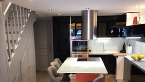 A modern kitchen with a central island, bar stools, a stainless steel range hood, and a built-in oven. - House for rent gulf of St Tropez 2 bedrooms in residence with swimming pool tennis (Gassin)